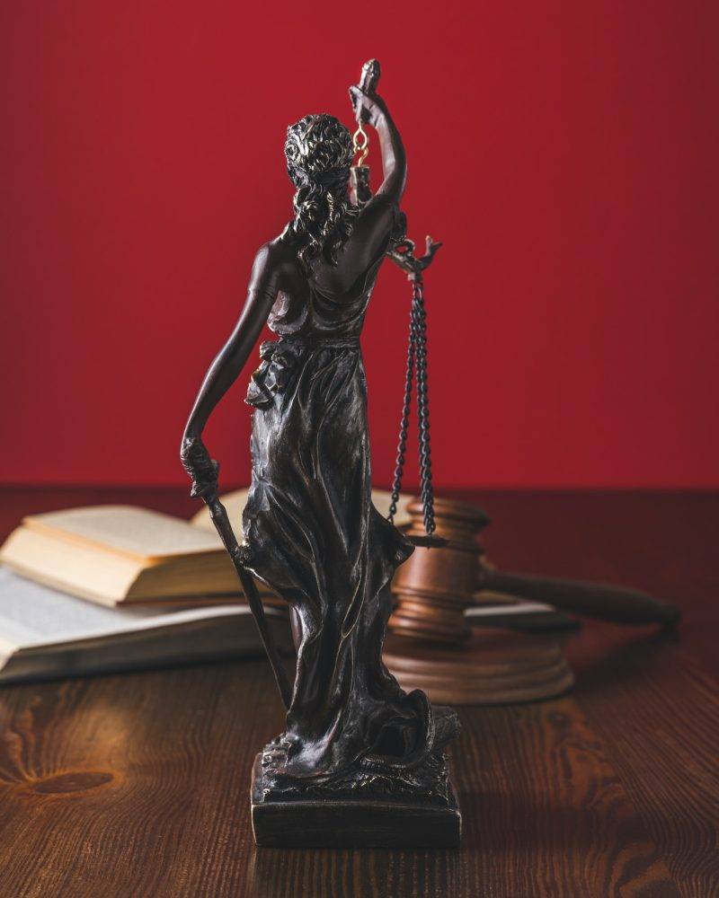 opened juridical books with lady justice statue on wooden table law concept